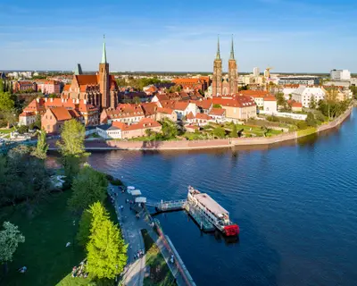 Poland. Wroclaw. Ostrow Tumski, Gothic cathedral of St. John the Baptist,  Collegiate Church of the Holy Cross, Archbishop's palace, tourist harbor, ship and Odra (Oder) River. Aerial view at sunset
