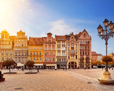 Central market square in Wroclaw Poland with old colourful houses, street lantern lamp and walking tourists people at gorgeous stunning morning sunrise sunshine. Travel vacation concept.