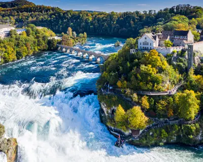Rhine Falls or Rheinfall, Switzerland panoramic aerial view. Tourist boat in waterfall. Bridge and border between the cantons Schaffhausen and Zurich. Cliff-top Schloss Laufen castle, Laufen-Uhwiesen.