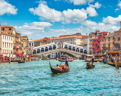 Bridge Rialto on Grand canal famous landmark panoramic view Venice Italy with blue sky white cloud and gondola boat water.