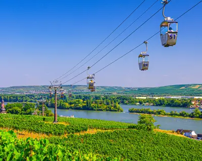 Cable car on rope of cableway from Rudesheim am Rhein town to Roseneck mount above vineyards fields of river Rhine Valley hills, blue clear sky background in sunny summer day, State of Hesse, Germany