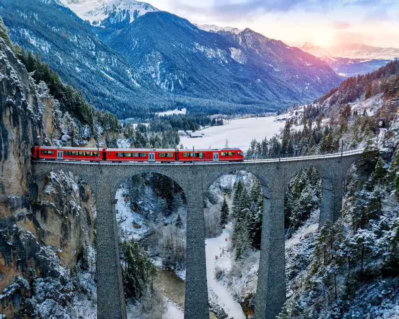 Aerial view of Train passing through famous mountain in Filisur, Switzerland. Landwasser Viaduct world heritage with train express in Swiss Alps snow winter scenery.
